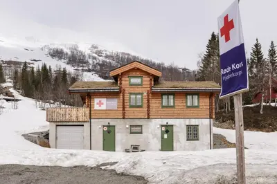 a log house with green doors in the snow at Røde Kors in Brunstad
