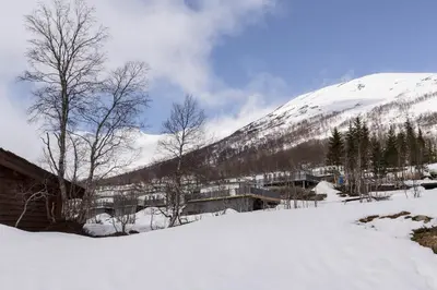 a snow covered mountain with a building in the background at Røde Kors in Brunstad