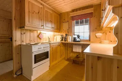 a kitchen with wooden cabinets and a white stove at Sjåfram in Stranda