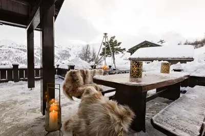 two dogs laying around a table in the snow at Strandafjellet Mountain Lodge in Stranda