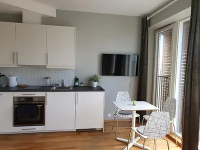 a kitchen with white cabinets and a table and chairs at Veversmauet Apartments in Bergen