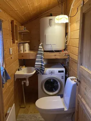a small bathroom with a washing machine and a sink at Haukeli Mountain Cabin in Vågsli