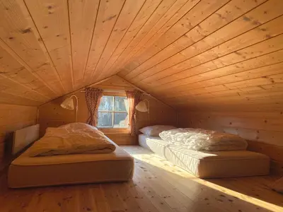 two beds in a room with a wooden ceiling at Haukeli Mountain Cabin in Vågsli