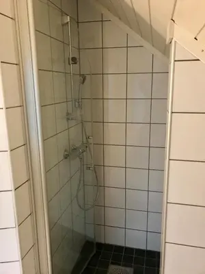 a shower in a bathroom with white tiles at Lodge Visnes Stryn in Stryn