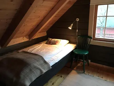 a bed in a room with a chair and a window at Lodge Visnes Stryn in Stryn