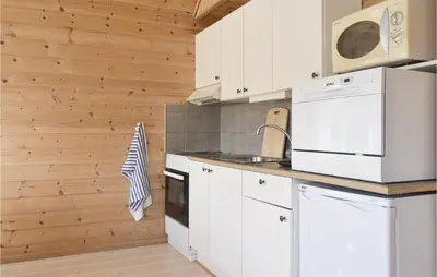 a kitchen with white appliances and a wooden wall at 3 Bedroom Nice Home In Vallavik in Vangsbygd