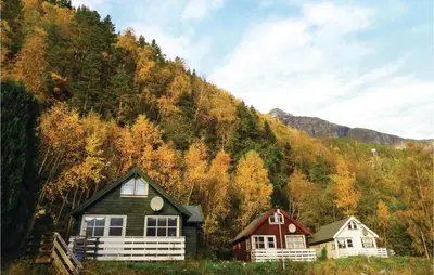 two houses are sitting in front of a mountain at Gorgeous Home In Vallavik With Wifi in Vangsbygd