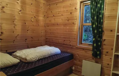 a bed in a log cabin with a window at Gorgeous Home In Vallavik With Wifi in Vangsbygd