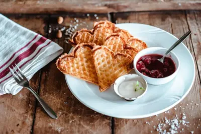 a white plate with waffles and a bowl of sauce at Venabu Fjellhotell in Venabygd