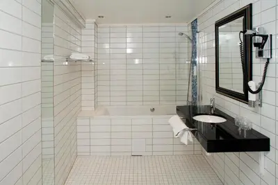a white tiled bathroom with a sink and a shower at Quality Hotel Prinsen in Trondheim