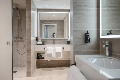 a bathroom with a tub and a sink and a mirror at Quality Hotel Prinsen in Trondheim