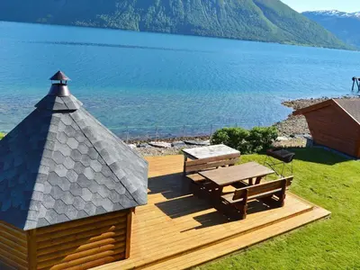a wooden deck with a picnic table and a lake at 5 person holiday home in EIDSVÅG in Eidsvåg