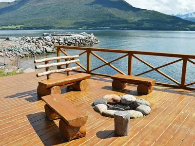 a wooden deck with two benches and a fire place at 5 person holiday home in EIDSVÅG in Eidsvåg