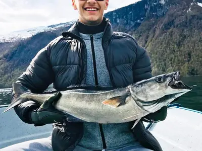a man holding a fish in front of a boat at 5 person holiday home in EIDSVÅG in Eidsvåg