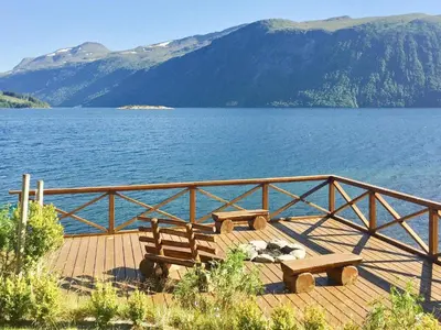 two benches sitting on a wooden deck overlooking a lake at 6 person holiday home in EIDSVÅG in Eidsvåg