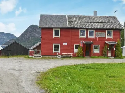 a red house with a bench in front of it at 4 person holiday home in Måndalen in Sæbø