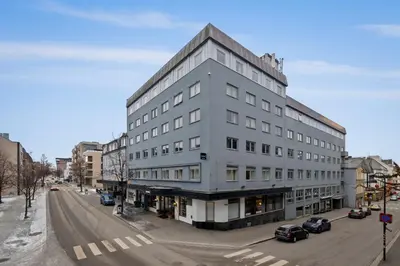 a large white building on a city street with cars at Home Hotel Astoria in Hamar