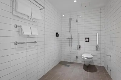 a white tiled bathroom with a toilet and a shower at Home Hotel Astoria in Hamar
