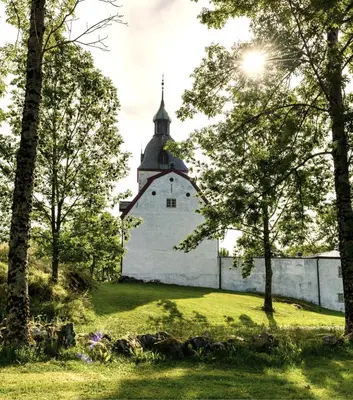 an old building in the middle of a field with trees at Ørland Kysthotell in Brekstad