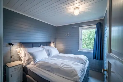 a bedroom with a bed with blue walls and a window at Hustadvika Havhotell - by Classic Norway Hotels in Farstad