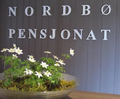 a bowl of flowers on a table in front of a sign at Nordbø Pensjonat in Hjartdal