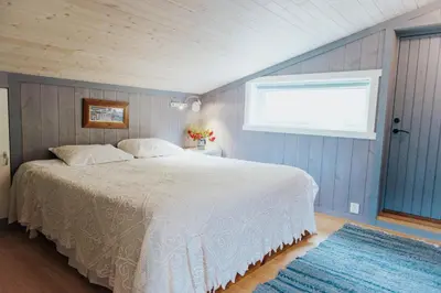 a bedroom with a white bed and a window at Ein heilt spesiell låve i Røldal in Røldal