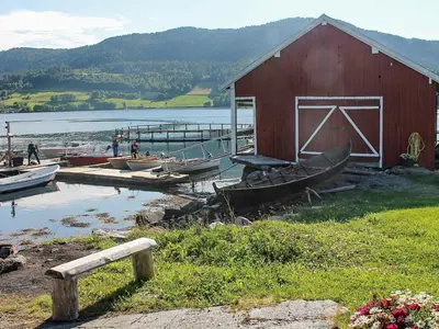 a barn and boats on the shore of a lake at 8 person holiday home in VÅGLAND-By Traum in Vågland