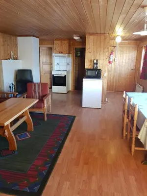 a living room with a table and a kitchen at Nybu Two-bedroom cottage in Geilo