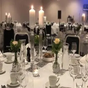 a table with vases with flowers and candles on it at Førde Hotel - Unike Hoteller in Førde