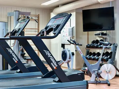 a gym with tread machines and a flat screen tv at Bardøla Fjelltun in Geilo
