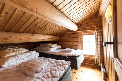 two beds in a room with wooden ceilings at Bardøla Fjelltun in Geilo
