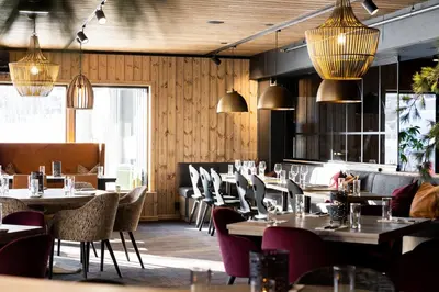 a restaurant with tables and chairs and pendant lights at Bardøla Fjelltun in Geilo