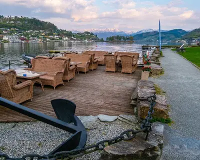 a group of tables and chairs on a dock next to the water at Thon Hotel Sandven in Norheimsund