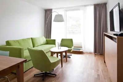 a living room with a green couch and chairs at Thon Hotel Sandven in Norheimsund