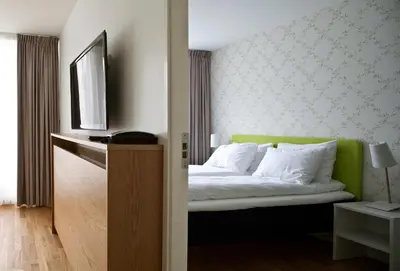 a bedroom with a bed with a green headboard at Thon Hotel Sandven in Norheimsund