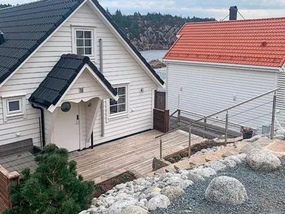 a white house with a wooden deck next to a building at 8 person holiday home in Urangsvåg-By Traum in Ervik