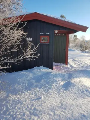 a black building with a red roof in the snow at Knutebu Two-Bedroom Cottage in Geilo