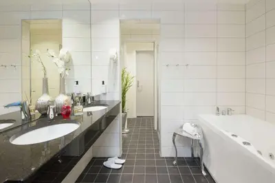 a white bathroom with two sinks and a tub and a tubermott at Thon Hotel Elgstua in Elverum