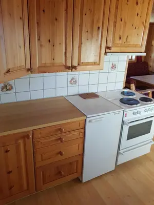a kitchen with wooden cabinets and a white stove top oven at Fjellbu Two-bedroom Cottage in Geilo