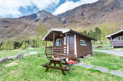 a small cabin with a picnic table in the grass at Flåm Hostel & Cabins in Flåm