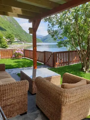 a patio with wicker chairs and a table and a lake at Bazyl Apartment in Folkedal