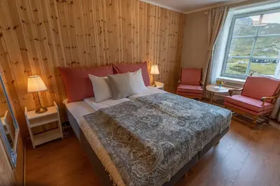 a bedroom with a large bed and two chairs at Bygdin Høyfjellshotell in Beitostøl