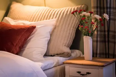 a vase of flowers on a table next to a bed at Bygdin Høyfjellshotell in Beitostøl