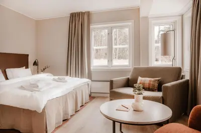 a hotel room with a bed and a chair and a table at Jegtvolden Fjordhotell in Straumen