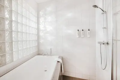 a white bathroom with a tub and a shower at Jegtvolden Fjordhotell in Straumen