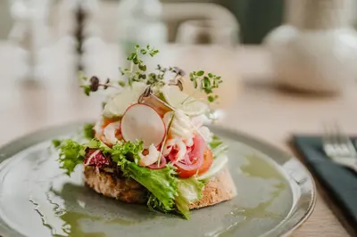 a sandwich on a plate with lettuce and tomatoes at Jegtvolden Fjordhotell in Straumen
