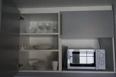 a kitchen with a microwave and plates and wine glasses at Orkla Camping in Orkanger