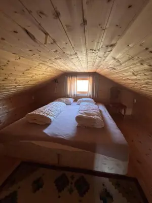 a large bed in a wooden room with a window at Bua in Viksdalen