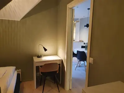 a bedroom with a desk and a bed and a lamp at Kong Oscars Apartments in Bergen