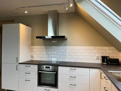 a kitchen with white cabinets and a stove at Kong Oscars Apartments in Bergen